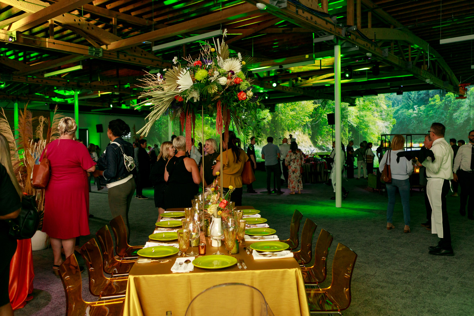 The interior of an event venue furnished with green lighting and tables with people enjoying a nonprofit event